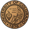 The image displays a round seal or emblem with the text  UNIVERSITY OF COLORADO  prominently at the top, followed by the year  1876  and the word  DENVER  beneath it. Below this text is an illustrated depiction of a torch flanked by two branches, one on each side. The seal has a circular border with a central design that includes a torch, two branches, and the words  Let your light shine.  Around the outer edge of the seal, there is a ring with a smaller inscription that reads  COLORADO  at the top and  1876  at the bottom. The background of the image is white, which contrasts with the golden color of the emblem.