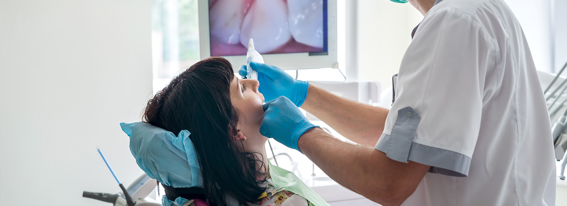 Dentist performing dental procedure with patient in chair.