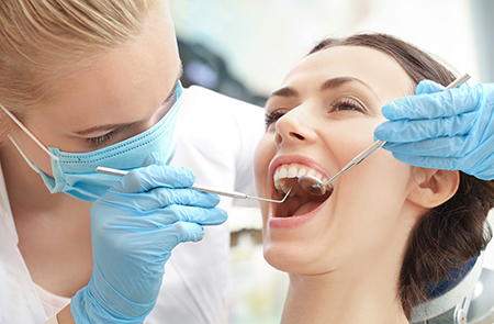 A dental hygienist assisting a patient with teeth cleaning, using specialized tools.